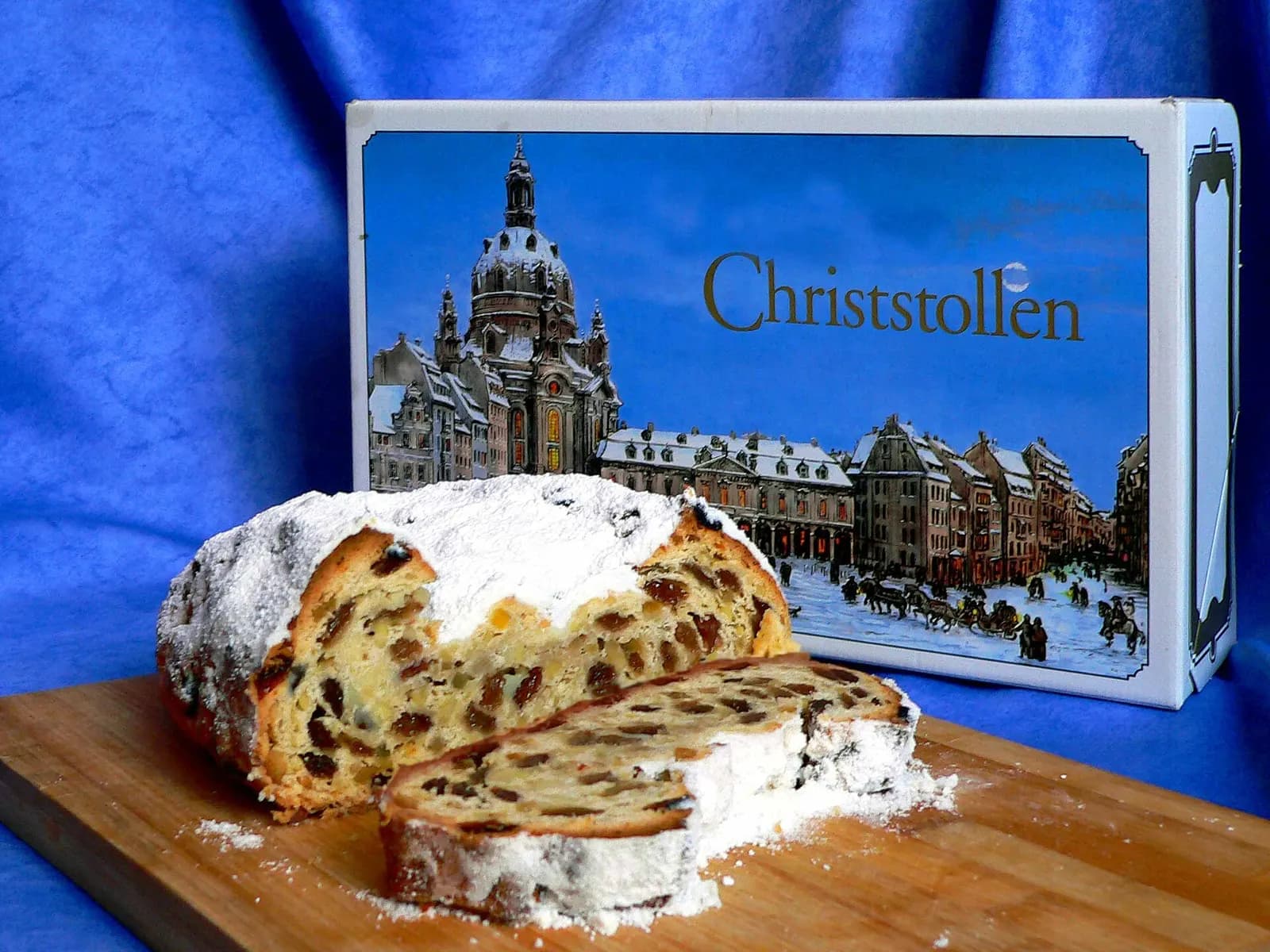 Angeschnittener Christstollen mit Puderzucker vor einer Stollenverpackung