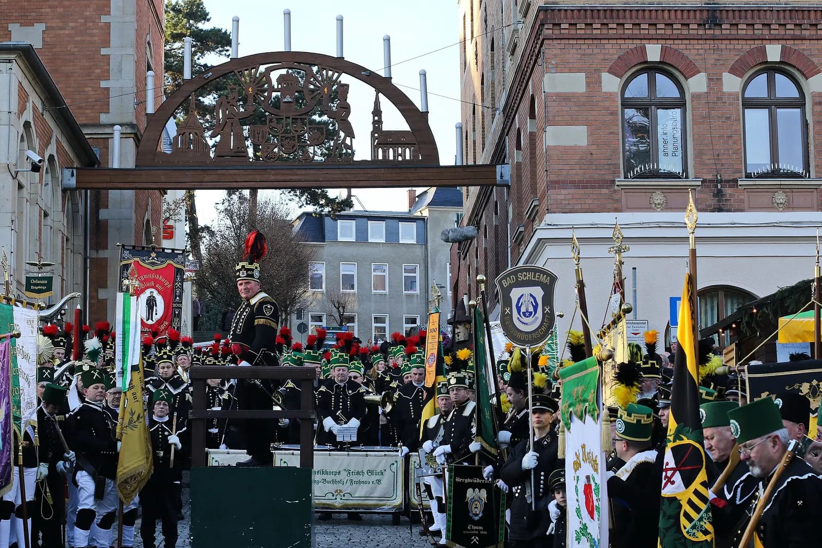 Bergleute in Paradeuniform mit Fahnen und Musikinstrumenten auf einem Platz