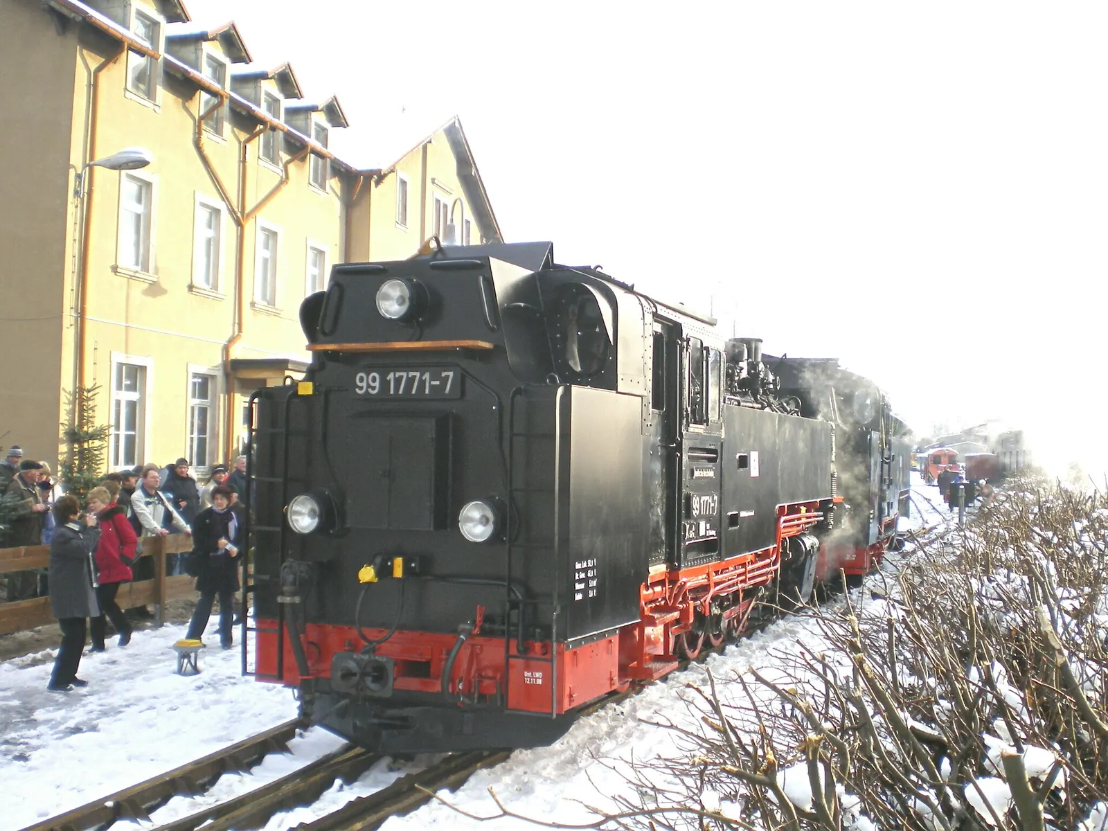 Dampflok der Weißeritztalbahn im Schnee am Bahnsteig, umringt von Fahrgästen