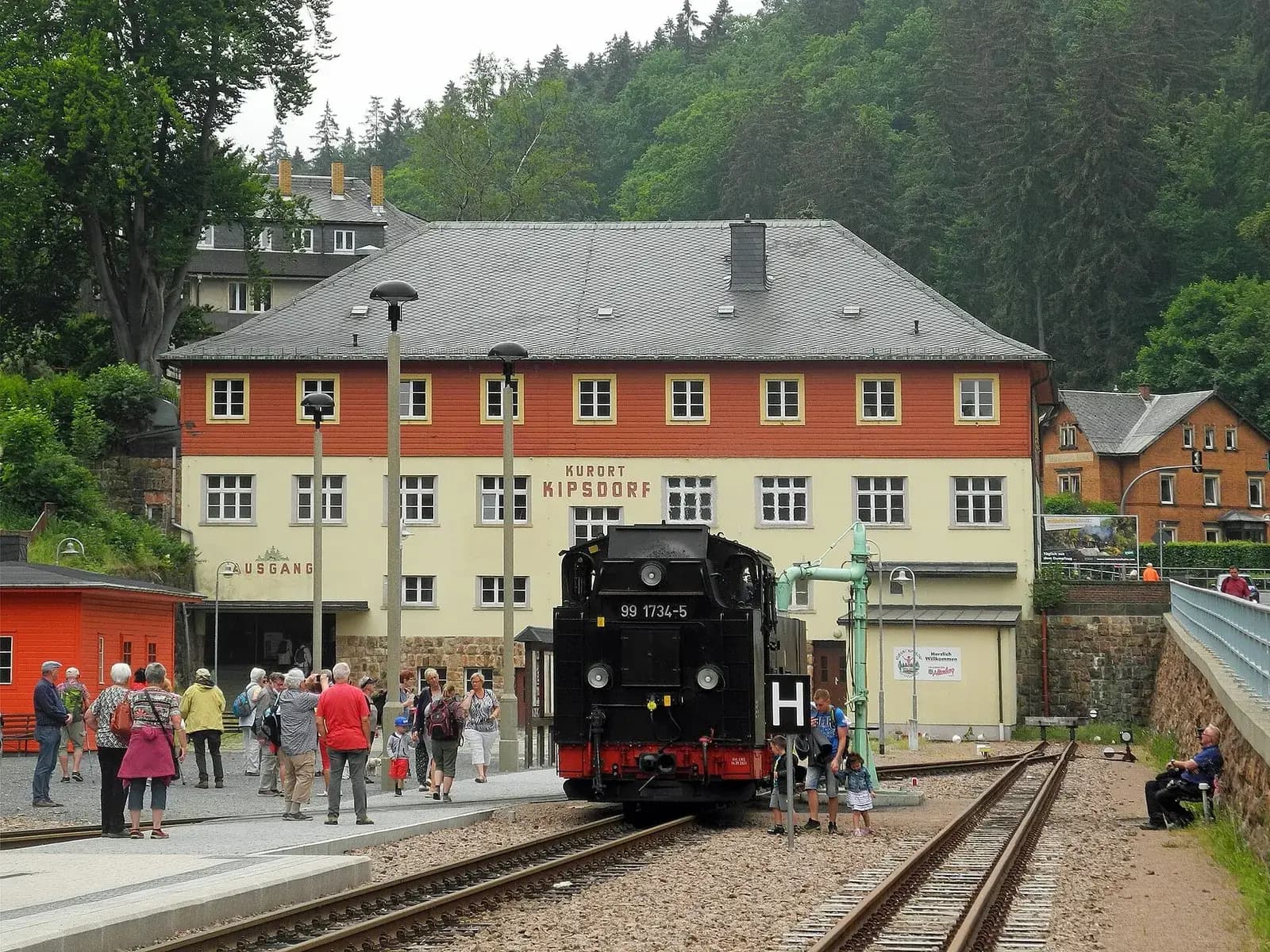 Dampflok der Weißeritztalbahn am Bahnsteig vor dem Bahnhofsgebäude Kurort Kipsdorf, Fahrgäste warten