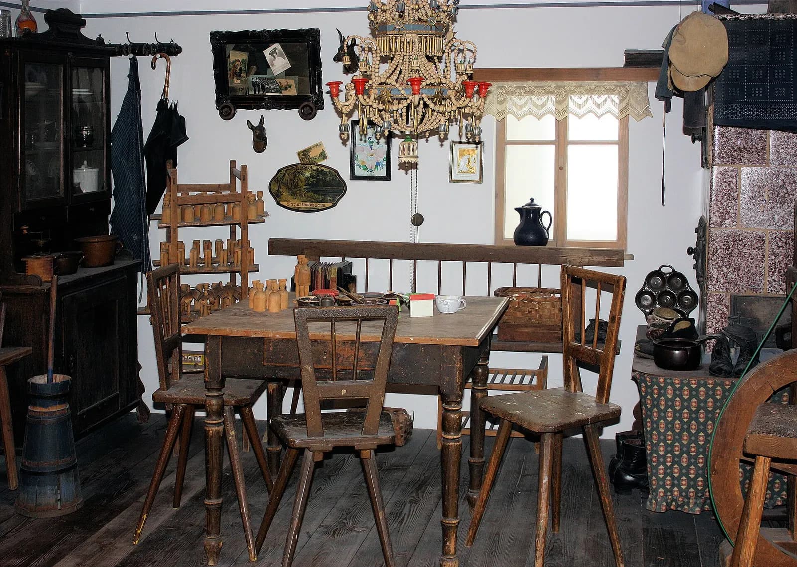 Nachgebaute Wohnstube um 1900 mit Holztisch, Stühlen, Hängeleuchter und Werkzeug an den Wänden